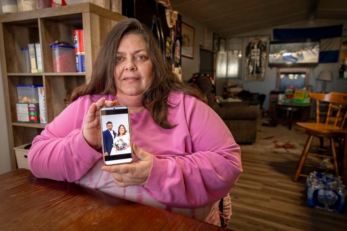 Stacey Murillo Martinez holds up a wedding photo of her and her husband Miguel on Nov. 17, 2025, in her home kitchen in Fond du Lac, Wis. ICE officers waited inside the Fond du Lac County Jail to take Miguel, an immigrant from Honduras, into custody — just after Stacey finished scraping together $1,500 to pay his bail in a criminal case. (Mike Roemer for Wisconsin Watch)