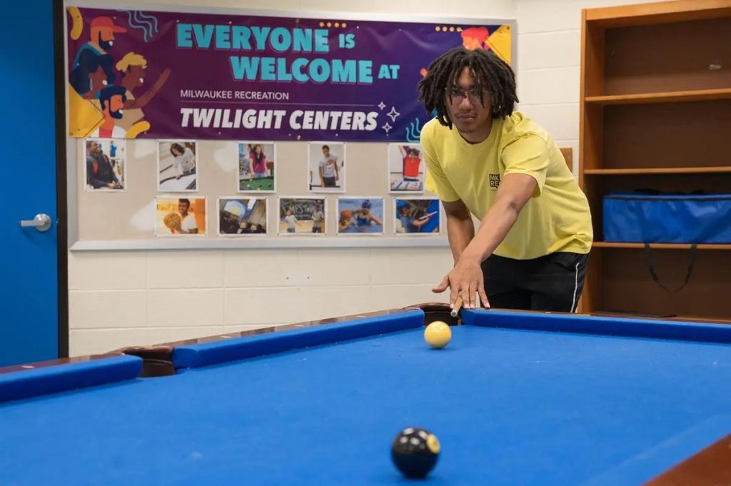Byrce Samuel, 17, plays pool in the Twilight Center game room at North Division High School. (Photo by Jonathan Aguilar / Milwaukee Neighborhood News Service / CatchLight Local)