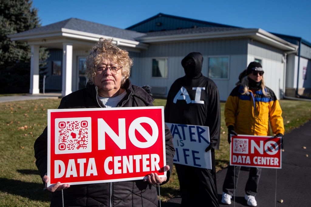 Joyce Skalitzky of Beaver Dam, left, holds a sign outside the venue of a data center announcement Wednesday, Nov. 12, 2025, in Beaver Dam, Wis. Angela Major/WPR