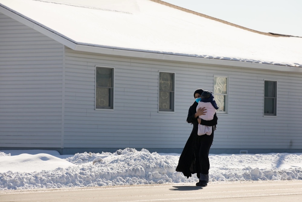 Afghan refugee carries her child at Ft. McCoy U.S. Army base. Photo by Sgt. Robert Wormley. (Public Domain).