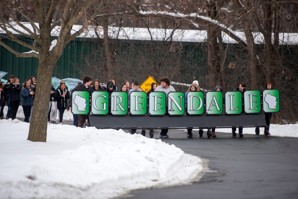 Members of the Greendale High School band roll a sign with their school name and the state of Wisconsin during rehearsal Tuesday, Dec. 9, 2025, in Greendale, Wis. Angela Major/WPR