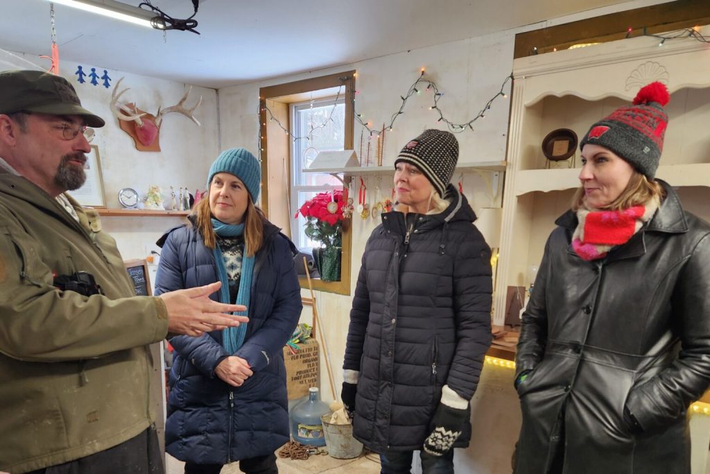 Senators and two current representatives seeking Senate seats in 2026 have been touring the state to highlight affordability and the effects of Republican policy choices, including tariffs and cuts to health care at the federal level. Senate Minority Leader Dianne Hesselbein, second from left, listens as Christmas Tree farm operator Lance Jensen discusses his business with Hesselbein and Sens. Sarah Keyeski and Melissa Ratcliff, during a visit to Jensen’s farm on Dec. 8. (Photo by Erik Gunn/Wisconsin Examiner)