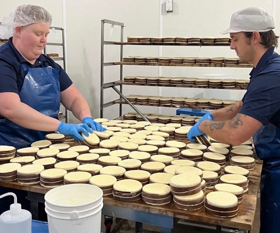 Hanna Lee and her colleague at Uplands Cheese Company in Dodgeville help prepare the iconic Rush Creek Reserve, a soft-ripened cheese wrapped in spruce bark. Photo courtesy of Hanna Lee