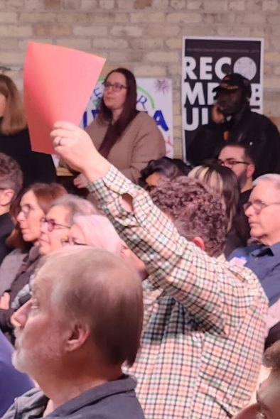 Shawn Phetteplace of Main Street Alliance holds up a red card to alert a forum speaker that their time for talking is up. (Photo by Erik Gunn/Wisconsin Examiner)