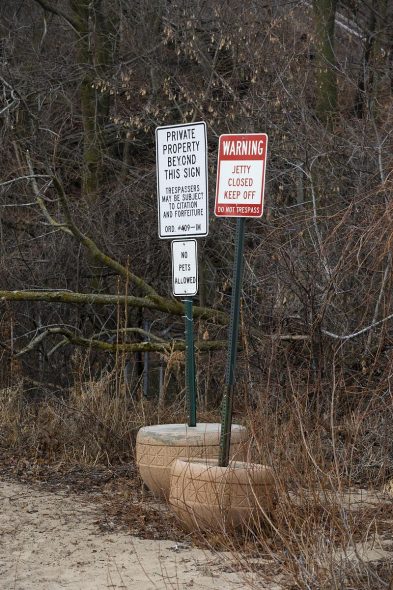 Signs warning against trespassing are posted on Jan. 8, 2026, at the border of Atwater Park in the village of Shorewood, Wis. Tiki compound owner Daniel Domagala seeks to preserve exclusive access to public beach along Lake Michigan’s shoreline. Unlike neighboring states, Wisconsin grants private owners exclusive use of publicly owned beach up to the Ordinary High Water Mark, which expands private control during low-water years. (Joe Timmerman / Wisconsin Watch)