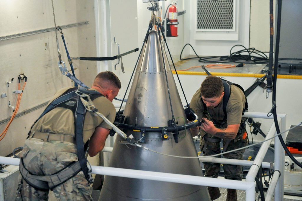 Senior Airman Jacob Deas and Airman 1st Class Jonathan Marrs secure a titanium shroud, beneath which is a nuclear warhead, at the top of a Minuteman III intercontinental ballistic missile, Aug. 24, 2023, at the Malmstrom Air Force Base in Great Falls, Montana. John Turner/U.S. Air Force via AP