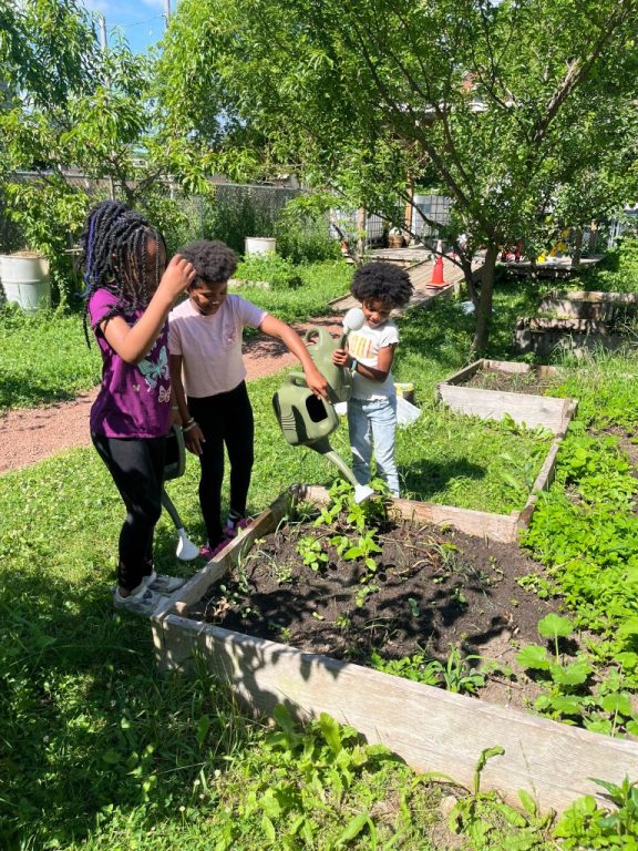 Children from We Got This Milwaukee work together to water plants. (Photo provided by Meg Bruzan)