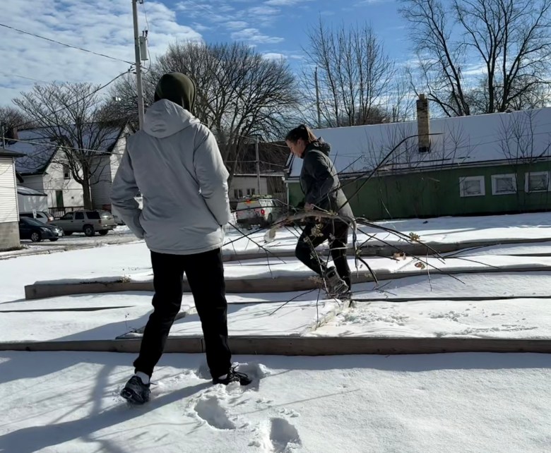 Denzil Brinson (front) helps Meg Bruzan remove a tree branch from Coaches Corner Garden between West Concordia Avenue and North 12th Street. (Photo by Chesnie Wardell)
