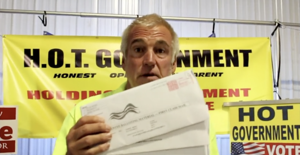 In a video, Harry Wait holds up absentee ballots he requested on behalf of other people. (Screenshot)