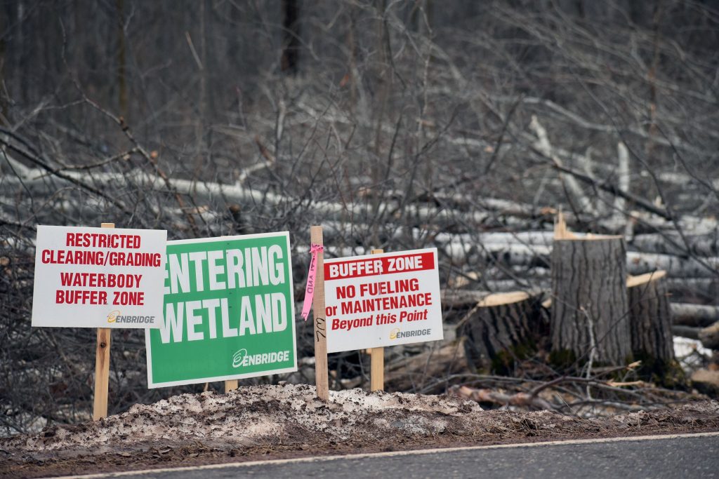 Signs show where a wetland and buffer zone for a waterway exist for Enbridge’s Line 5 reroute. Around 100 workers are clearing trees, staking the route or monitoring the project, according to a company official. Danielle Kaeding/WPR