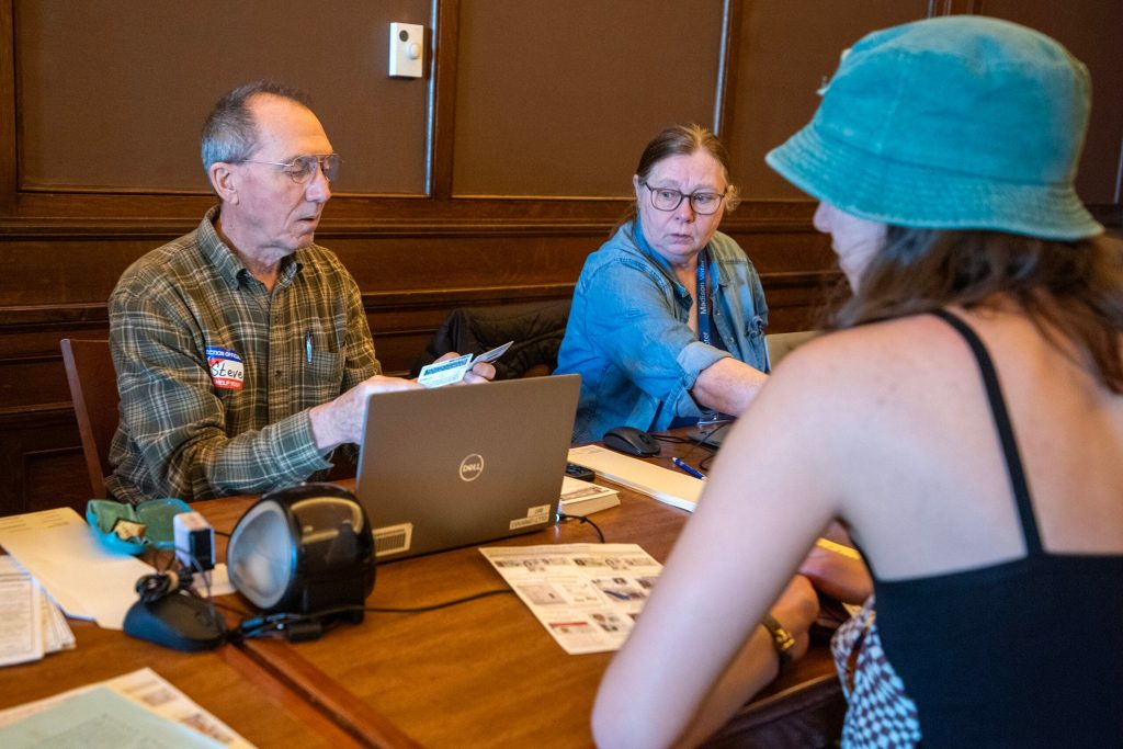 UW-Madison student Madeleine Afonso presents identification to vote early in-person Friday, March 28, 2025, in Madison, Wis. Angela Major/WPR