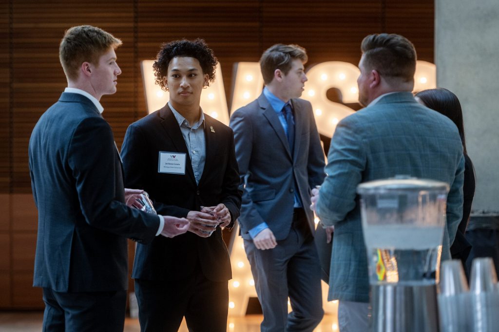 Jai Kozar-Lewis, a supply chain management major from Michigan State University, second from left, networks during an employer showcase Friday, March 20, 2026, at UW-Madison in Madison, Wis. Angela Major/WPR