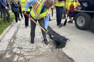 Mayor Cavalier Johnson fills a pothole in the Johnson's Woods neighborhood. Photo by Jeramey Jannene.