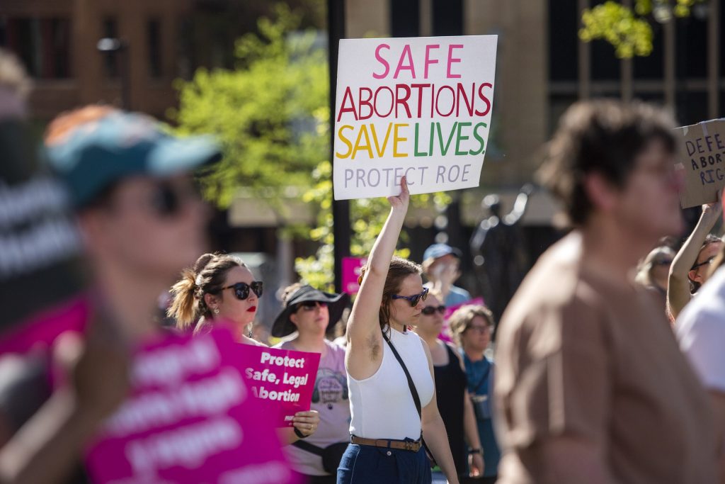 A protester in support of abortion access raises a sign in the air Saturday, May 14, 2022, at the Wisconsin state Capitol in Madison, Wis. Angela Major/WPR