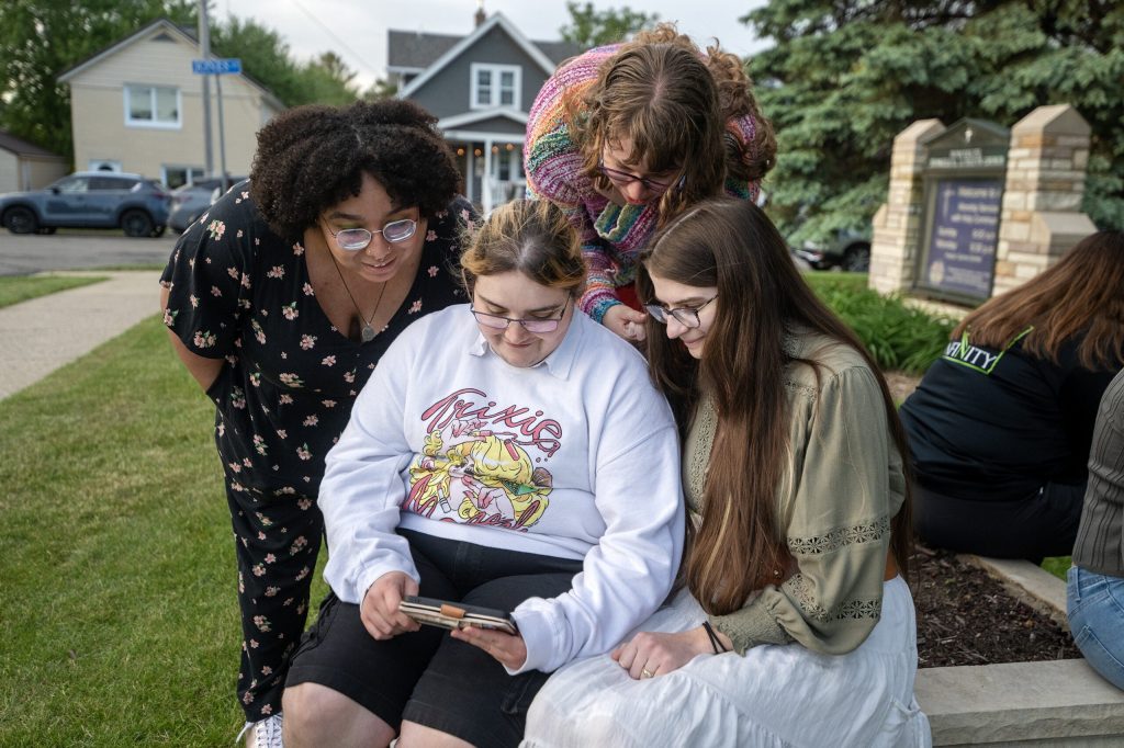 A group from Madison sits together around a phone as they watch the performance on live stream Wednesday, May 20, 2026, at Immanuel Evangelical Lutheran Church in Watertown, Wis. Angela Major/WPR