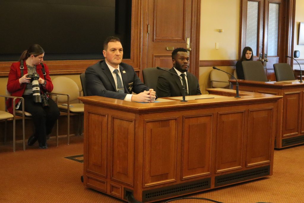 Detective Joseph Mensah (right) sits before the Senate Committee on Judiciary and Public Safety in 2025 pushing for a bill to protect police officers from John Doe investigations after fatal shootings. (Photo by Isiah Holmes/Wisconsin Examiner)