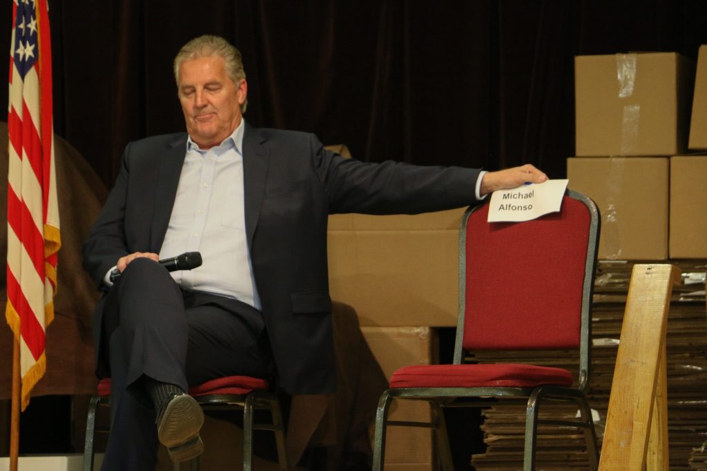 Republican 7th Congressional District candidate Kevin Hermening poses for a photo next to fellow candidate Michael Alfonso’s empty chair during an April 22 Iron County Republican Party debate in Mercer. Rich Kremer/WPR
