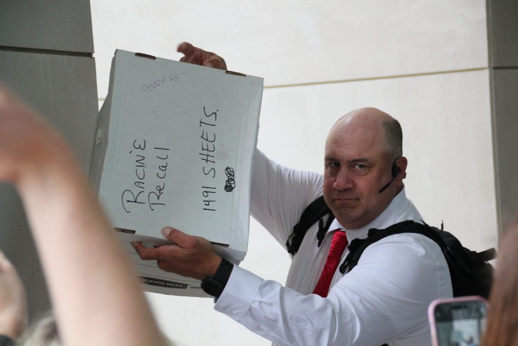 Matthew Snorek, one of the organizers of an effort to recall Assembly Speaker Robin Vos, holds up a box of what he says contains more than 9,000 signatures. Shawn Johnson/WPR