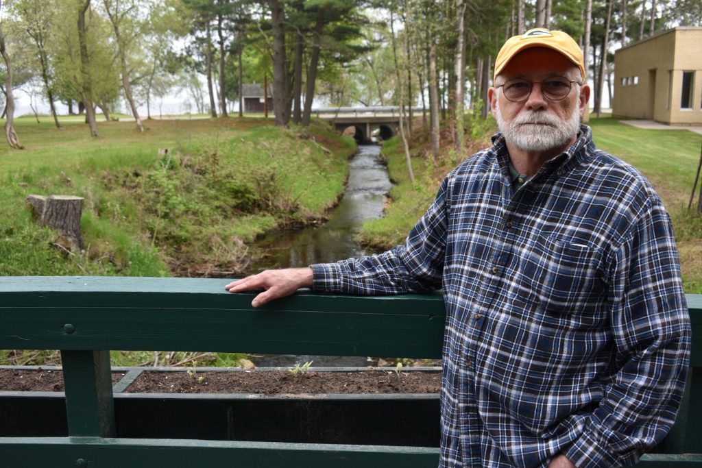 Marinette resident Doug Oitzinger stands over a ditch flowing into Green Bay where water samples have shown PFOS levels as high as 2,000 parts per trillion before it’s treated. Danielle Kaeding/WPR