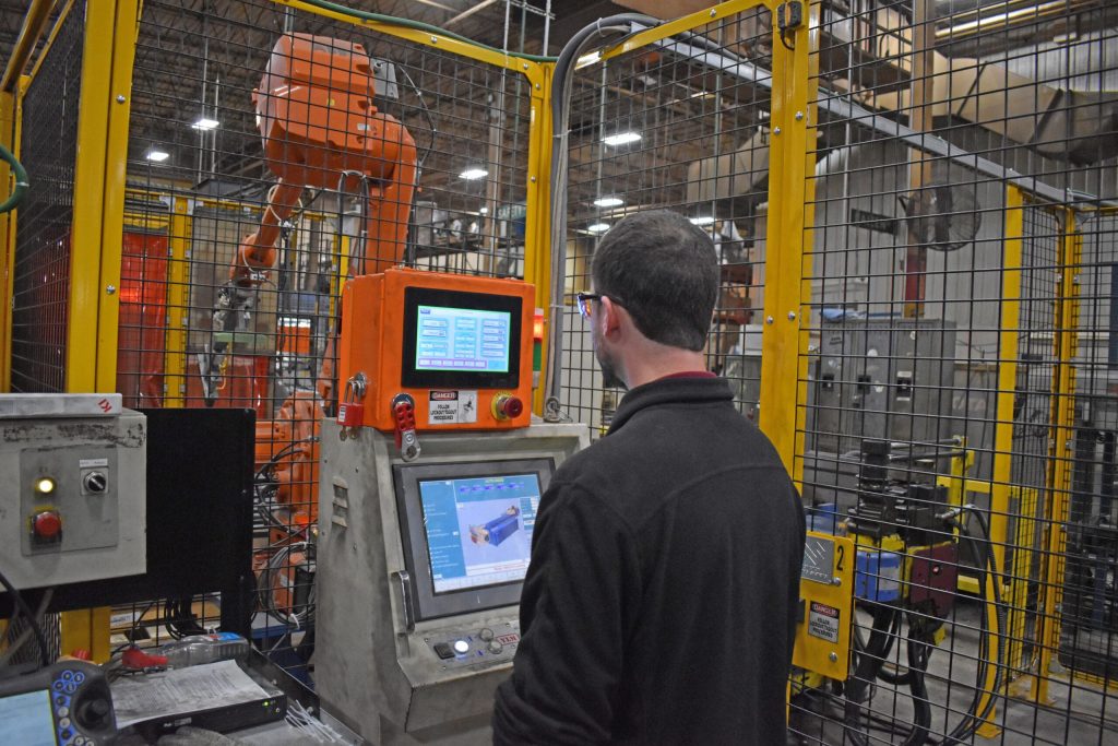Alex Peters, automation engineering manager for Green Bay furniture manufacturer KI, programs a computer on one of the company’s machines. Joe Schulz/WPR