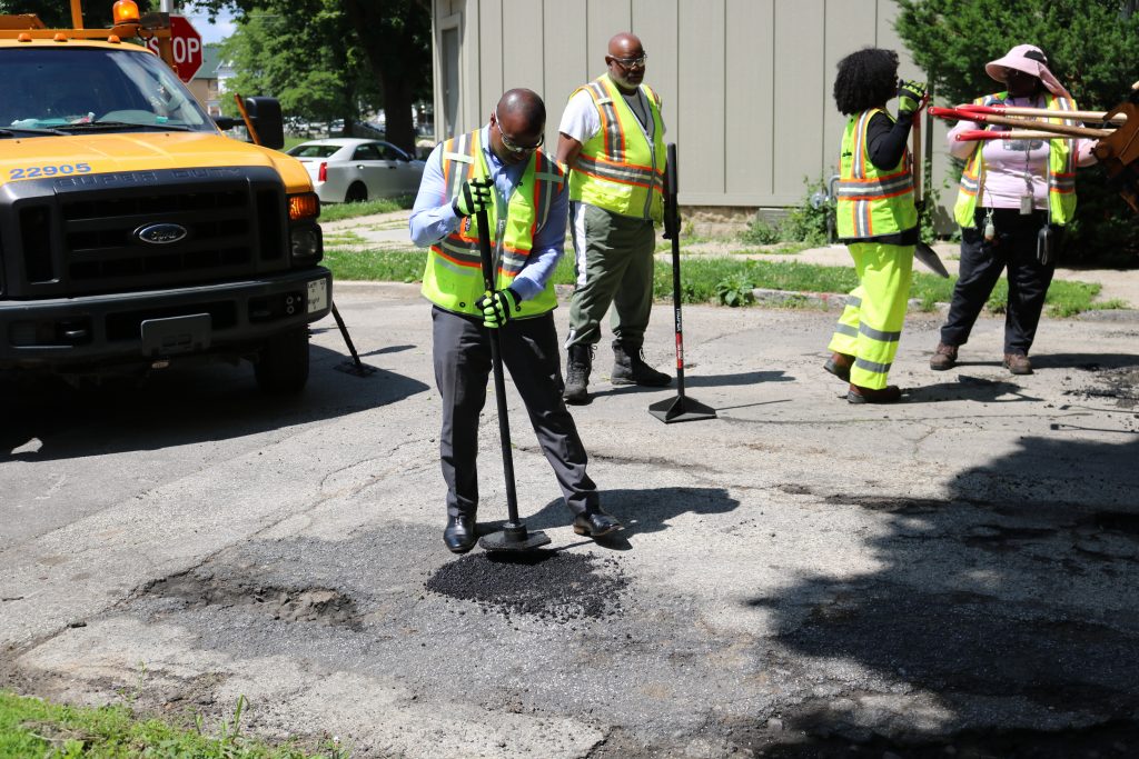 Mayor Cavalier Johnson fills a southside pothole with asphalt. Photo taken June 25, 2026 by Sophie Bolich.