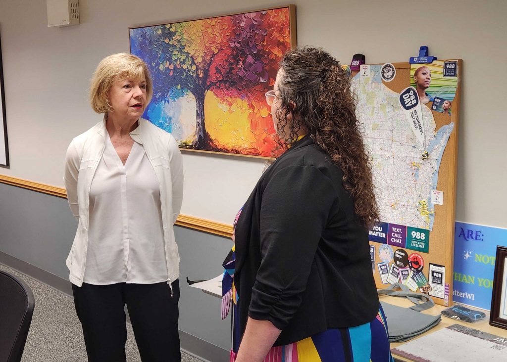 U.S. Sen. Tammy Baldwin, left, speaks with Jacci Preuss, a 988 training supervisor for Family Services of Northeast Wisconsin, right, during a tour of the facility on Friday, June 26, 2026. Joe Schulz/WPR