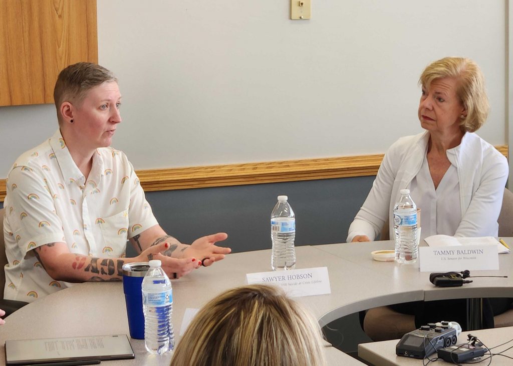 Sawyer Hobson, a 988 Lifeline Counselor at Family Services of NEW, left, speaks with U.S. Sen. Tammy Baldwin, right, during a roundtable discussion on Friday, June 26, 2026. Joe Schulz/WPR
