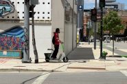 An individual rides a scooter on a sidewalk in downtown Milwaukee. Photo by Jeramey Jannene.