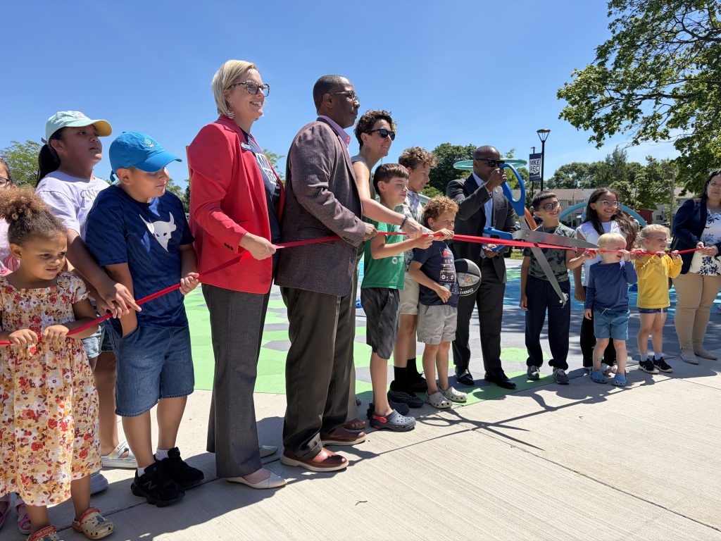 Annie Kubes, Brian D. Litzsey, Ald. Marina Dimitrijevic and Mayor Cavalier Johnson were surrounded by kids for the ribbon-cutting ceremony at Emigh Playfield. Photo taken June 22, 2026 by Sophie Bolich.