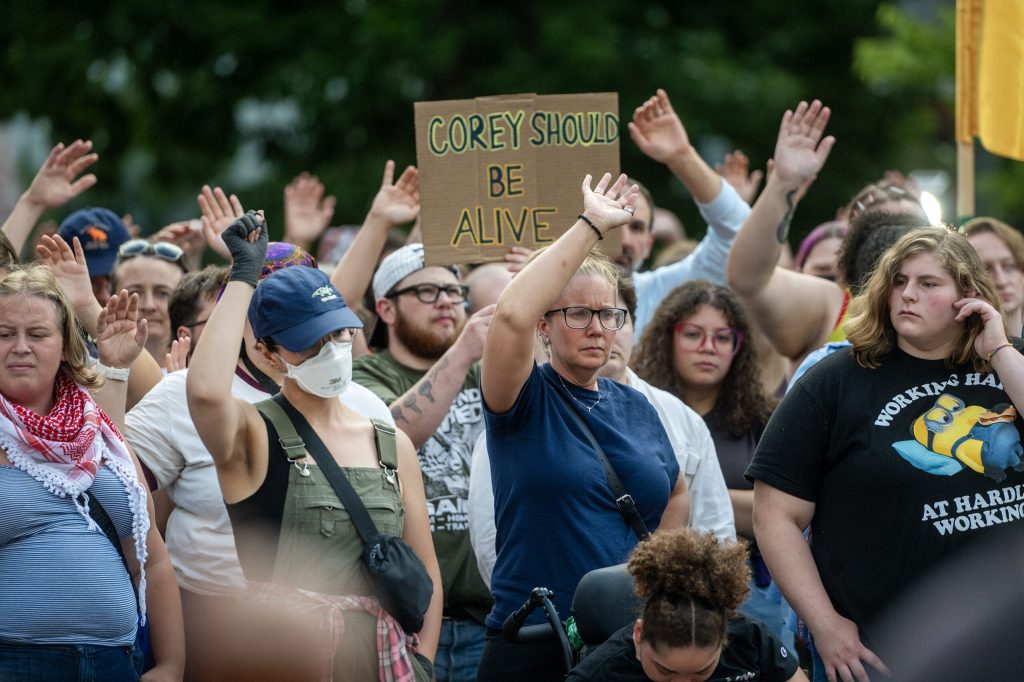 People raise their hands as music plays at a vigil for Corey Ruiz, a man who was shot and killed by Madison police, on Thursday, July 23, 2026, in Madison, Wis. Angela Major/WPR