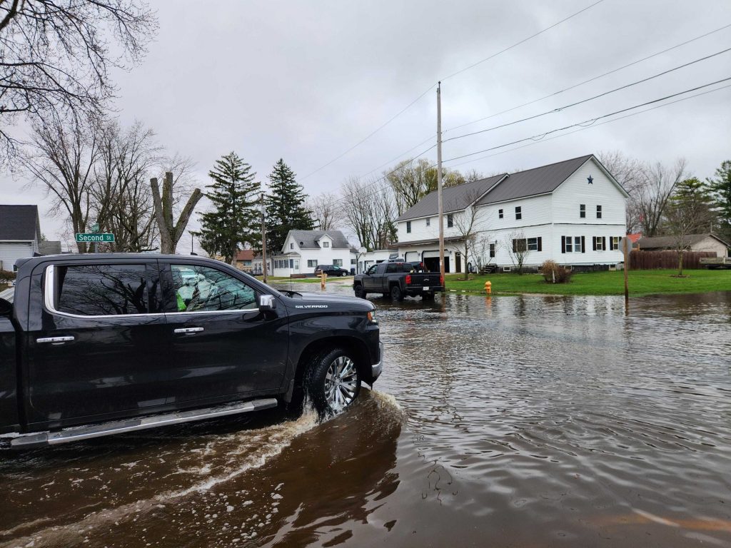 A pickup truck drives through a flooded street in Shiocton, Wis., on April 15, 2026. Joe Schulz/WPR