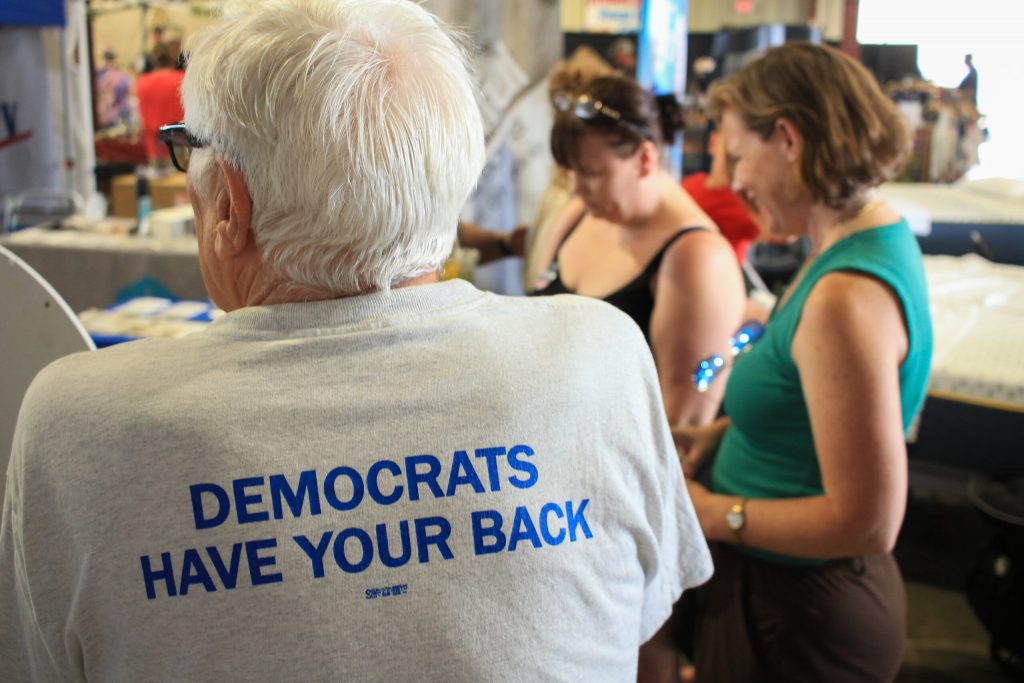 Emily Berge speaks with voters at the Democratic Party booth at the La Crosse County Fair. (Photo by Henry Redman | Wisconsin Examiner)