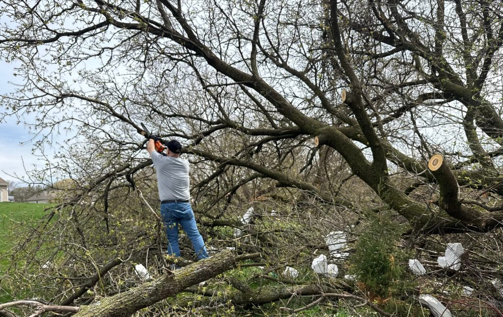 A homeowner cleans up debris left behind from a storm in the village of Lisbon. Evan Casey/WPR