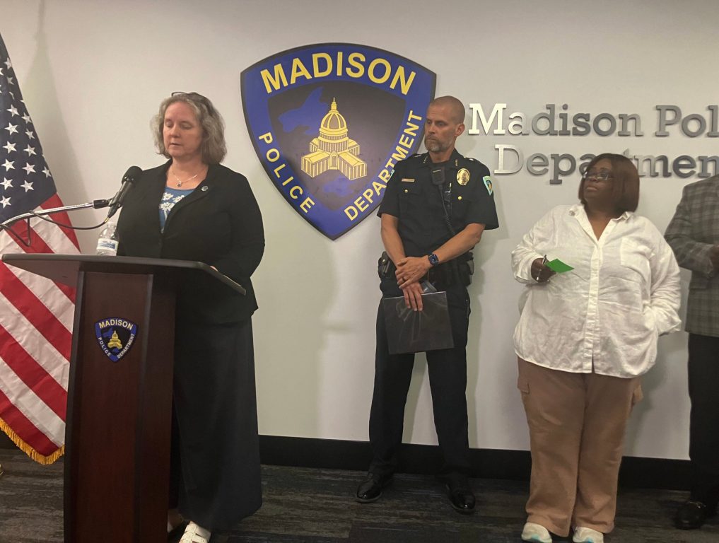 Madison Mayor Satya Rhodes-Conway, left, speaks at a press conference on Thursday, June 23, 2026, regarding the police shooting that killed Corey Ruiz, 38. Next to her stands Madison Police Chief John Patterson and Madison Common Council President Sabrina Madison. Sarah Lehr/WPR
