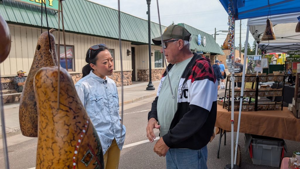 Hong speaks to Bob Boesch, Pam’s husband, among the thunder gourds they sell. (Photo by Baylor Spears/Wisconsin Examiner)