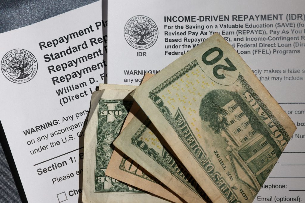 A stack of money sits on top of a couple of student loan repayment plan applications on Dec. 31, 2025, in Milwaukee. (Jonathan Aguilar / Milwaukee Neighborhood News Service / CatchLight Local)