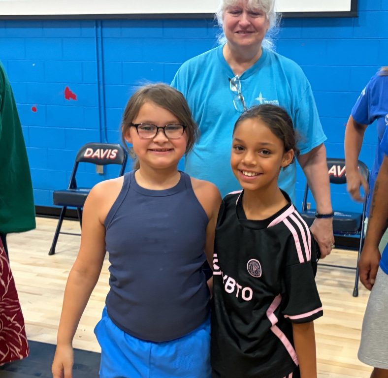 Aurora, 7, and Lilyanie, 9, are best friends who attended Lincoln Avenue School and say they’re excited to move to Pulaski High School in the Fall where their older brothers go. They’re pictured during a community meeting at Rogers Street Academy in Milwaukee, Wis. on July 13, 2026. Corrinne Hess/WPR
