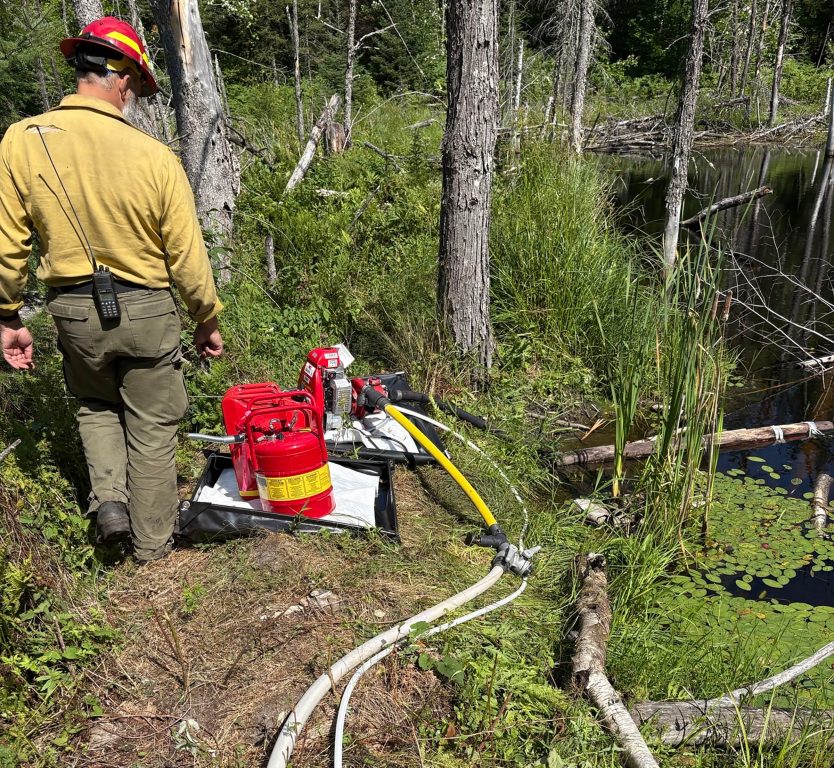 A pump is set up to draw water from a pond as firefighters run a mile of hose through the forest to put out smoldering segments of the Chub Fire. Photo courtesy of the Wisconsin DNR