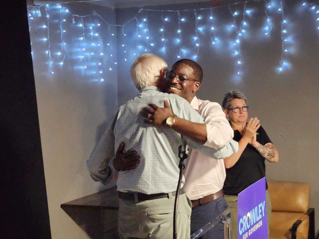 Milwaukee County Executive David Crowley, right, hugs Gov. Tony Evers at a campaign rally on Monday, Aug. 3, 2026, in Appleton, Wis. Joe Schulz/WPR