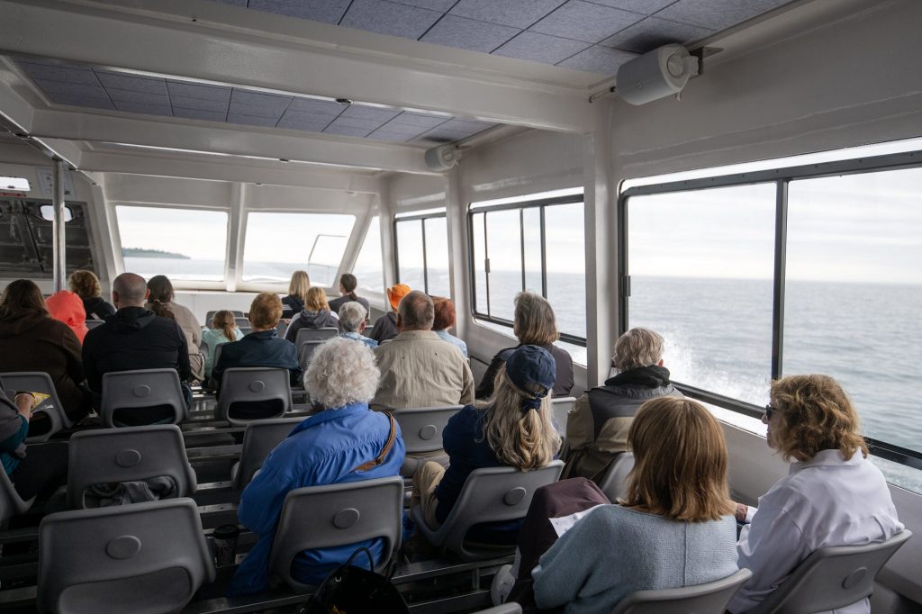 People look out windows at the Apostle Islands during a cruise Wednesday, July 8, 2026, in Bayfield, Wis. Angela Major/WPR