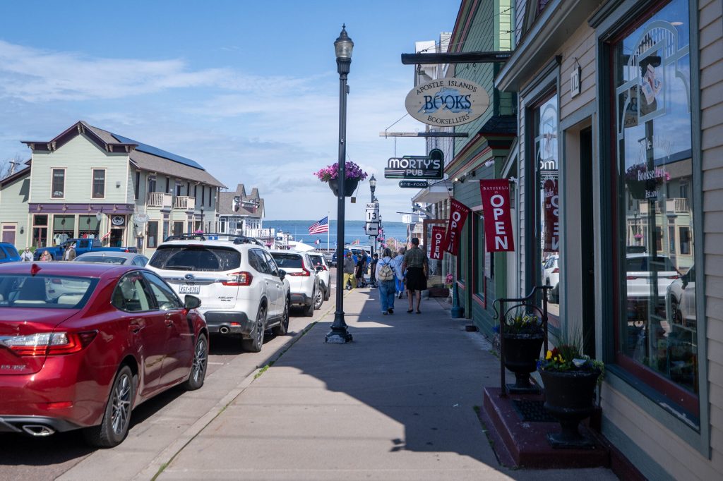Pedestrians stroll on the sidewalk past businesses Wednesday, July 8, 2026, in Bayfield, Wis. Angela Major/WPR