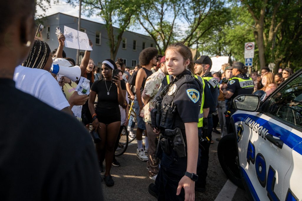 A Madison police officer stands near a squad car as protesters approach Wednesday, July 22, 2026, in Madison, Wis. Angela Major/WPR