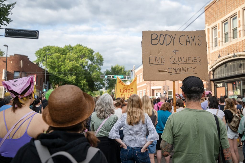 People hold signs as they listen to speakers at a vigil for Corey Ruiz on Thursday, July 23, 2026, in Madison, Wis. Angela Major/WPR