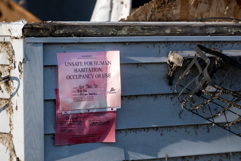 A sign hangs on the exterior of a home damaged by a tornado Tuesday, Aug. 25, 2026, in Menasha, Wis. Angela Major/WPR