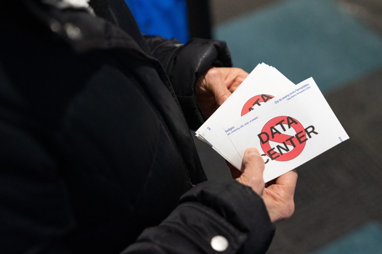 Sheri Stach hands out stickers opposing the QTS data center development before a DeForest Village Board meeting at Village Hall in DeForest, Wisconsin, on Jan. 20, 2026. The village later dropped the project following public opposition. (Kayla Wolf for Wisconsin Watch)