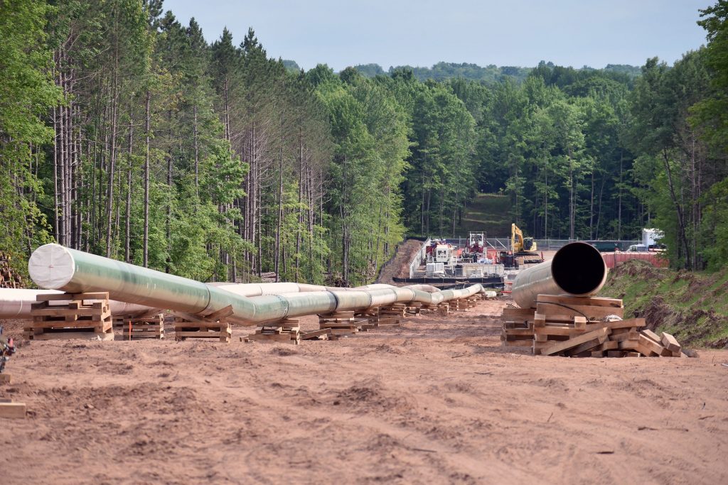 Construction equipment can be seen in the background of pipes staged for Enbridge’s Line 5 reroute in Iron County on June 28, 2026. Danielle Kaeding/WPR