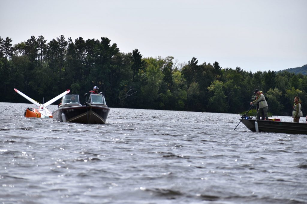 The plane, at the left, had been in Lake Wausau since the emergency landing on Sept. 12. The plane was connected to boats and floatation devices. Avery Martinez/WPR
