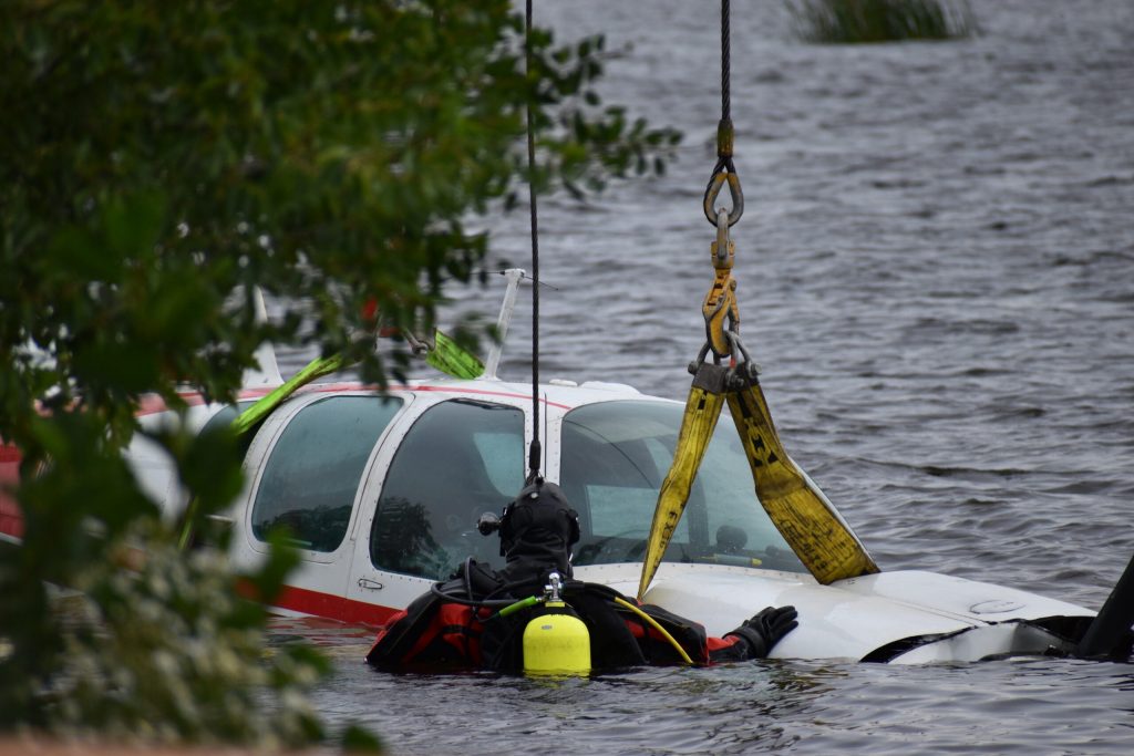 Divers work with the lowering cables to connect the plane to the straps. Avery Martinez/WPR
