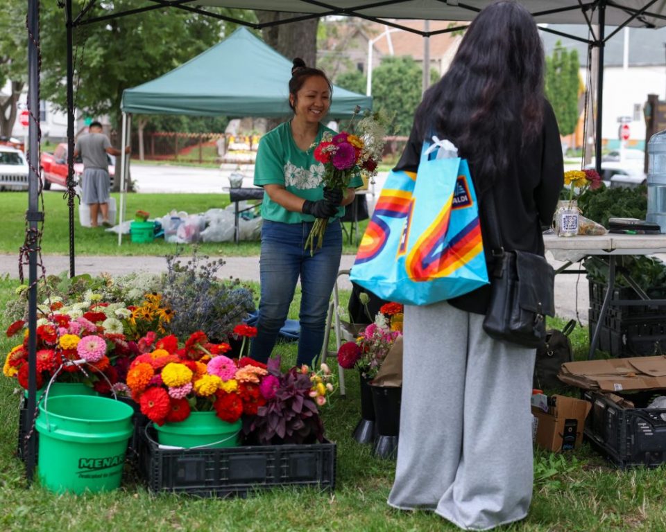 Rosa Yang, owner of Grandpa Khoua’s Farm, sells a bouquet of freshly picked flowers at the Walker Square Farmers Market on Aug. 9. (Photo by Jonathan Aguilar / Milwaukee Neighborhood News Service / CatchLight Local)