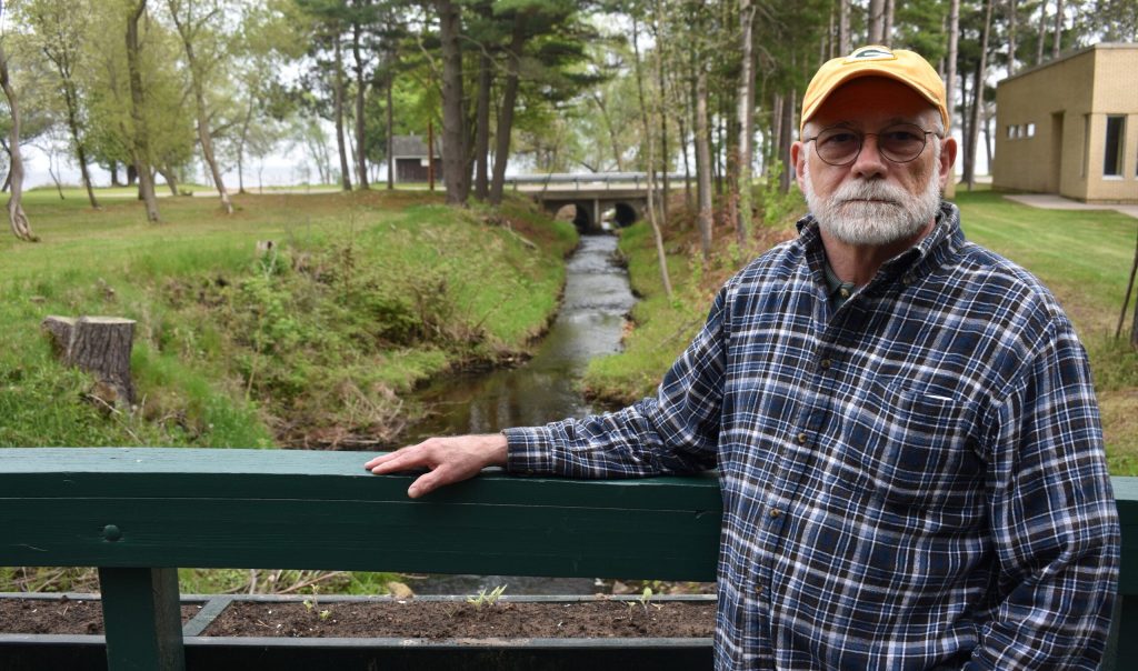 Marinette City Council member Doug Oitzinger stands over a ditch flowing into Green Bay where water samples have shown PFOS levels as high as 2,000 parts per trillion before it’s treated. Danielle Kaeding/WPR